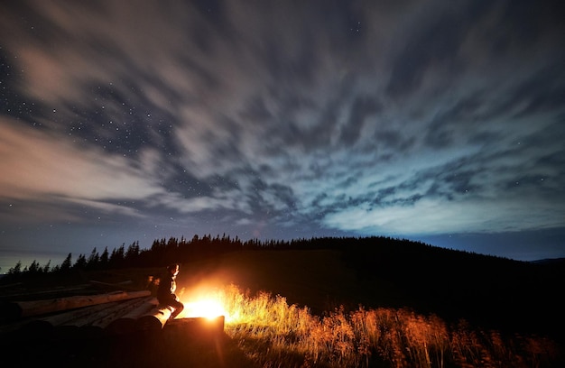 Young man relaxing near bonfire in mountains