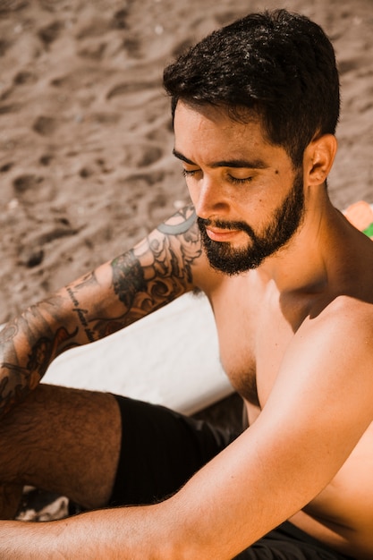 Young man relaxing near surfboard