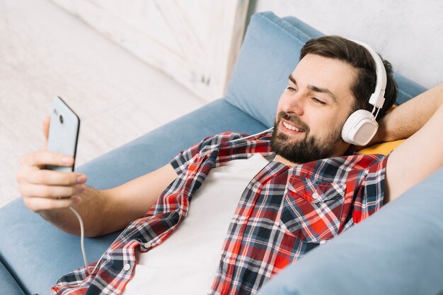 Young man relaxing on sofa with smartphone