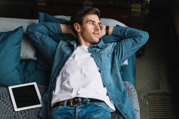 Young man relaxing with digital tablet on bed