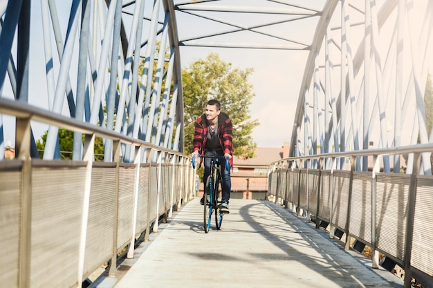 Young man riding bicycle on bridge