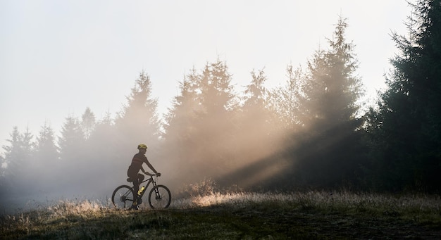 Бесплатное фото Молодой человек едет на велосипеде в горах рано утром
