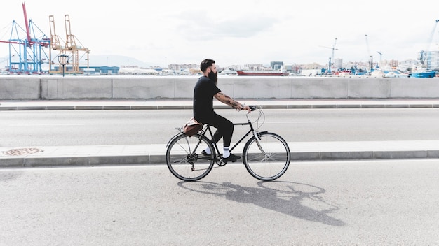 港の近くの道路で自転車に乗る若い男