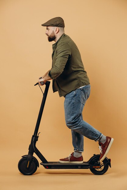 Young man riding electric scooter isolated on background in studio