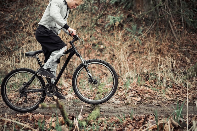 Foto gratuita giovane che guida la sua bicicletta sulla strada non asfaltata