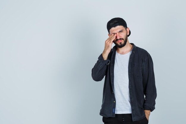 Young man rubbing eyes with fingers