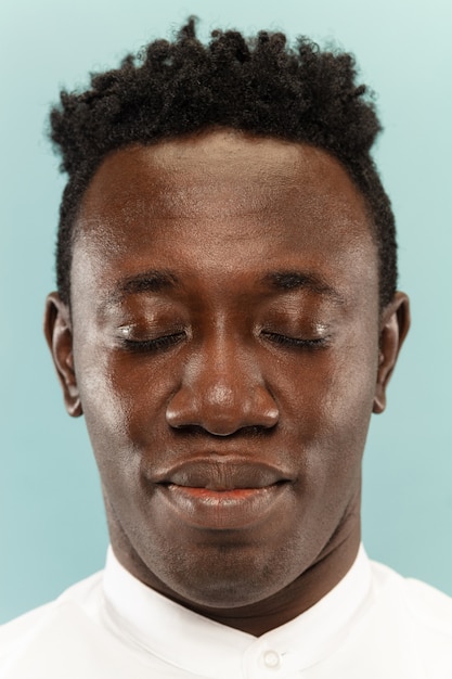 Young man's close up portrait on blue wall