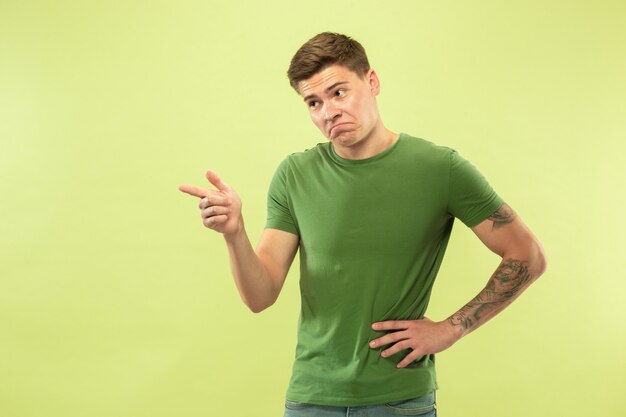 Young man's half-length portrait on green studio wall