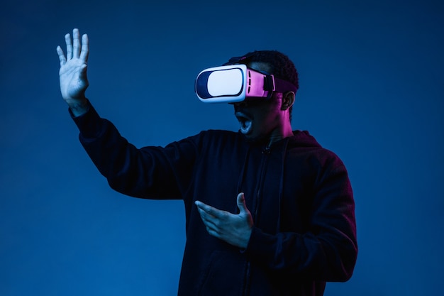 Young man's playing in VR-glasses in neon light on blue