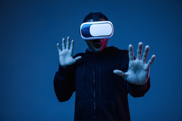 Young man's playing in VR-glasses in neon light