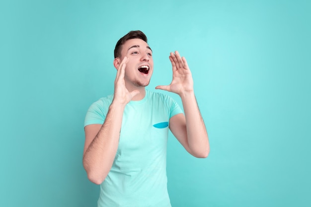 Young man's portrait isolated on blue studio wall