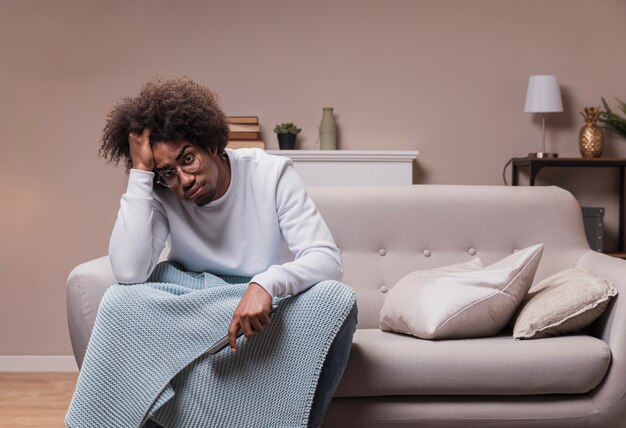 Young man sad on couch with remote