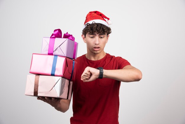 Young man in Santa hat looking at time.