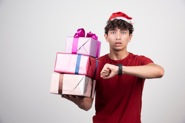 Young man in Santa hat looking at time.