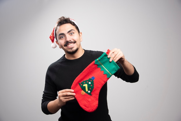 A young man in a Santa's hat holding a Christmas sock .