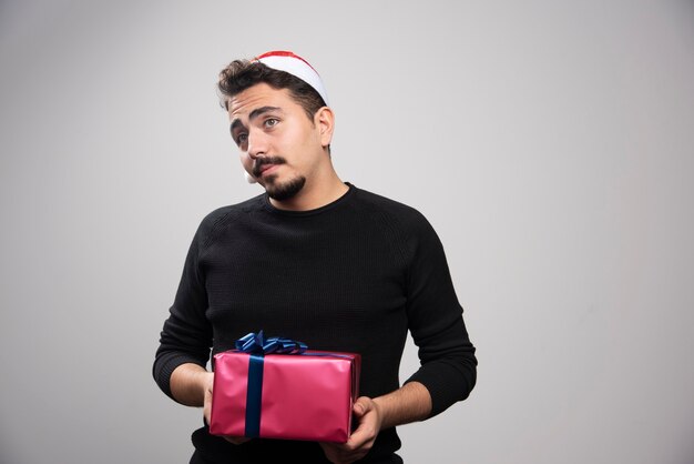 새해 선물을 들고 산타의 모자에있는 젊은 남자.