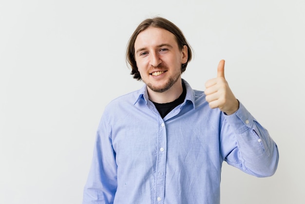 Young man say yes showing thumbs up in approval praise good job smiling approvingly standing on white background