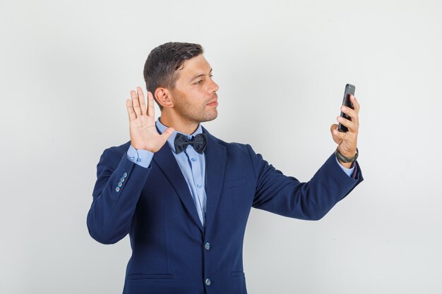 Young man saying hello on videocall in suit