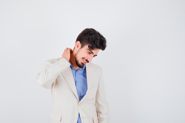 Foto gratuita giovane che si gratta il collo in camicia blu e giacca bianca e sembra felice looking