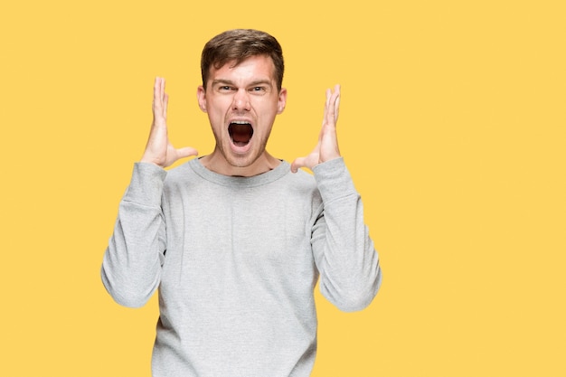 young man screaming with delight on yellow studio background