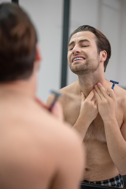 Young man shaving and looking concentrated