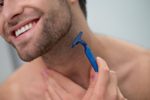 Free photo young man shaving at the mirror