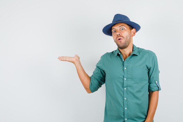 Young man in shirt, hat holding hand as catching something