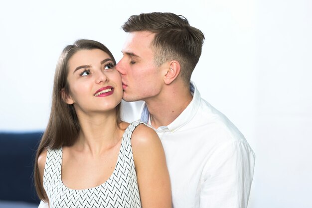 Young man in shirt kissing woman on cheek