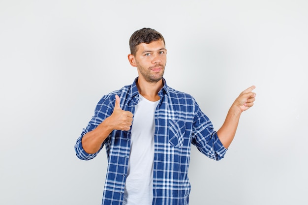Молодой человек в рубашке, указывая пальцем вверх и оптимистично глядя, вид спереди.