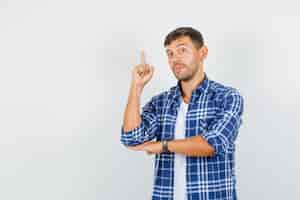 Free photo young man in shirt pointing finger up and looking confident, front view.