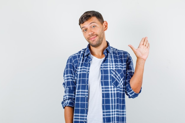 Young man in shirt showing up palm and looking funny , front view.