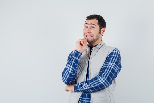 Young man in shirt,sleeveless jacket expressing positive emotions and looking glad , front view. space for text