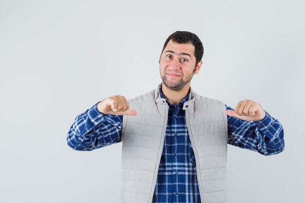 Young man in shirt,sleeveless jacket pointing at himself and looking confident , front view.