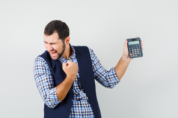 Giovane uomo in camicia, giubbotto azienda calcolatrice