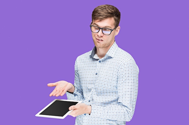 薄紫色の背景にラップトップに取り組んでシャツの若い男