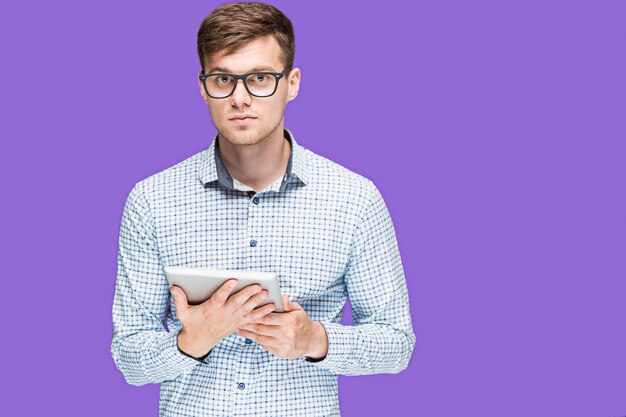 The young man in a shirt working on laptop on lilac wal