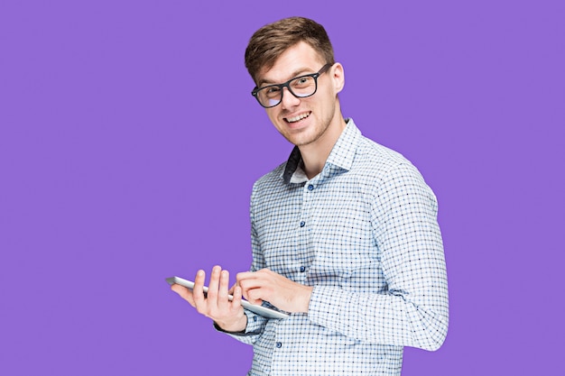 Free photo young man in a shirt working on laptop on purple