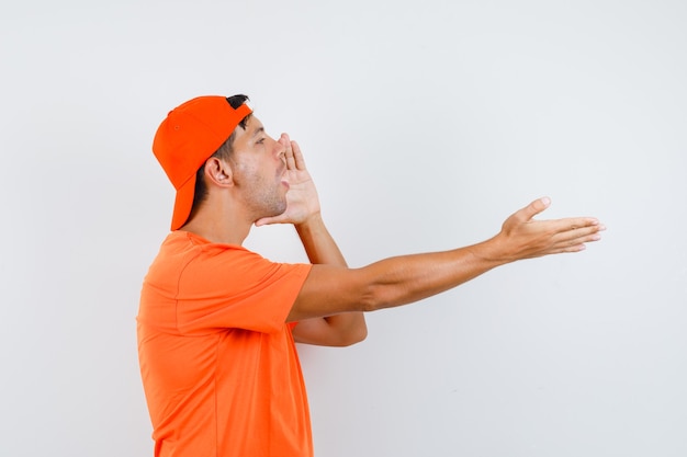 Young man shouting to somebody in orange t-shirt and cap .