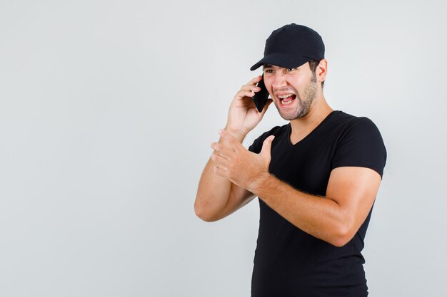 Young man shouting while talking on smartphone in black t-shirt