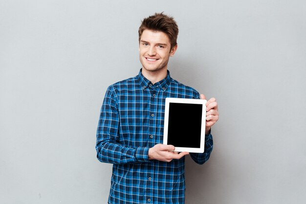 Молодой человек показывая пустой экран изолированного планшета