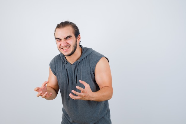 Young man showing claws imitating cat in hooded t-shirt and looking crazy , front view.