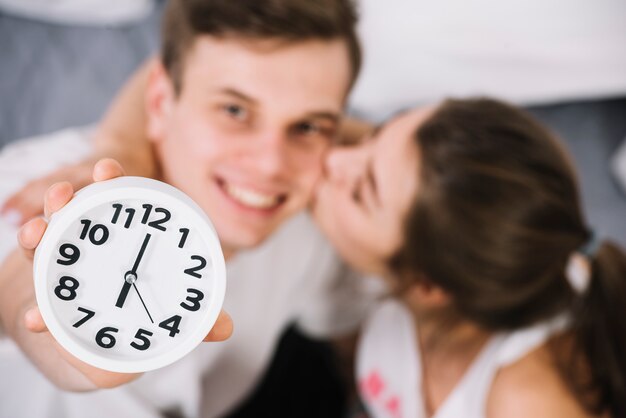 Young man showing clock with 6am