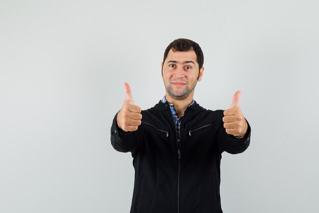 Young man showing double thumbs up in shirt, jacket and looking confident , front view.