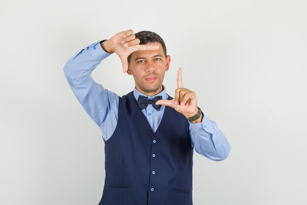 Young man showing frame gesture with fingers in suit and looking glad 