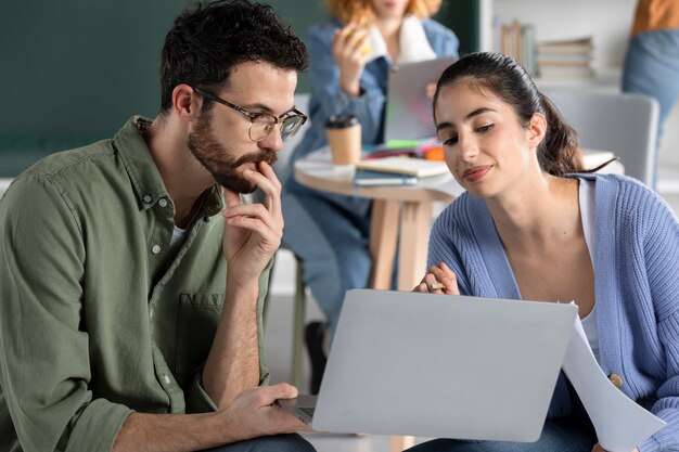 Young man showing his colleague information from his laptop