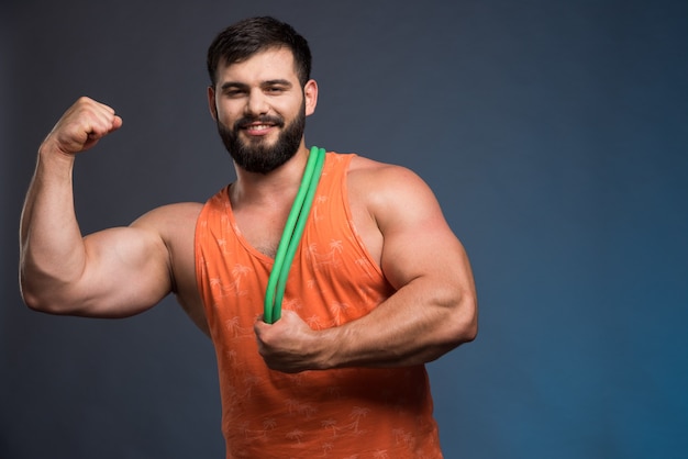 Young man showing his muscles and holding rubber for sport.