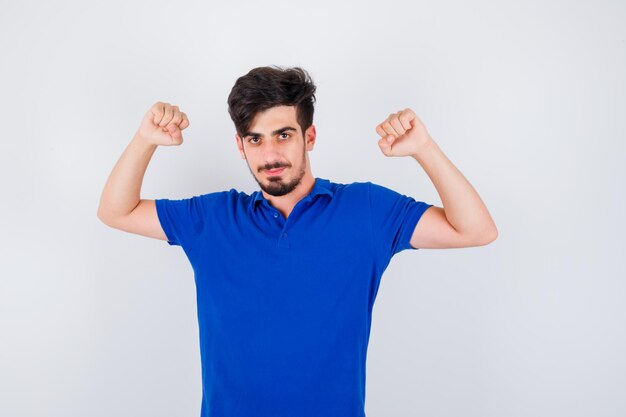 Young man showing muscles in blue t-shirt and looking serious