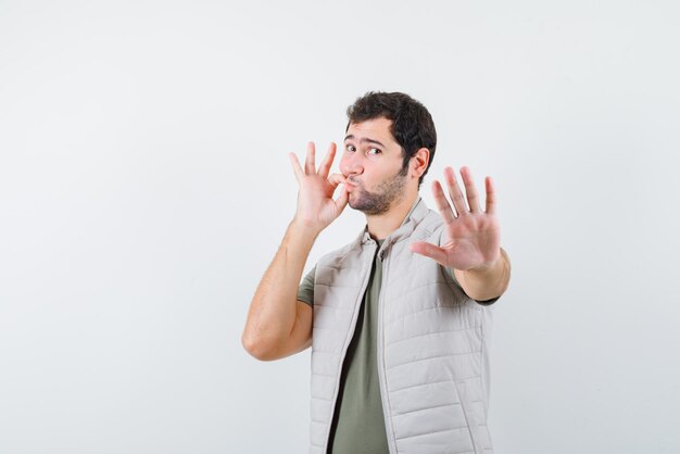 Young man showing an OK hand sign and doing a stop hand sign on white background