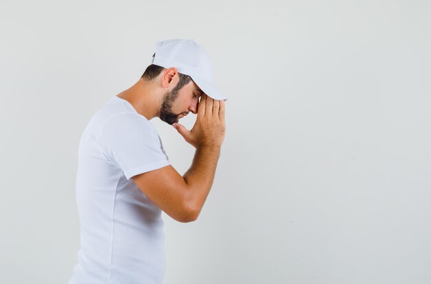 Young man showing praying gesture in t-shirt and looking wishful. . space for text