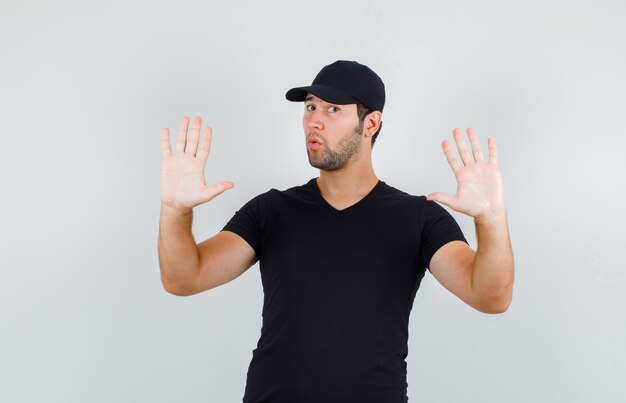 Молодой человек показывает жест отказа в черной футболке